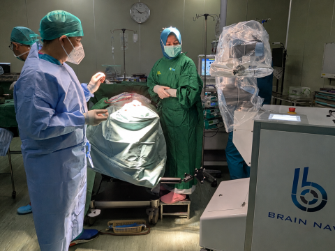 Neurosurgical team operating with the Brain Navi NaoTrac robotic navigation system in an operating room.